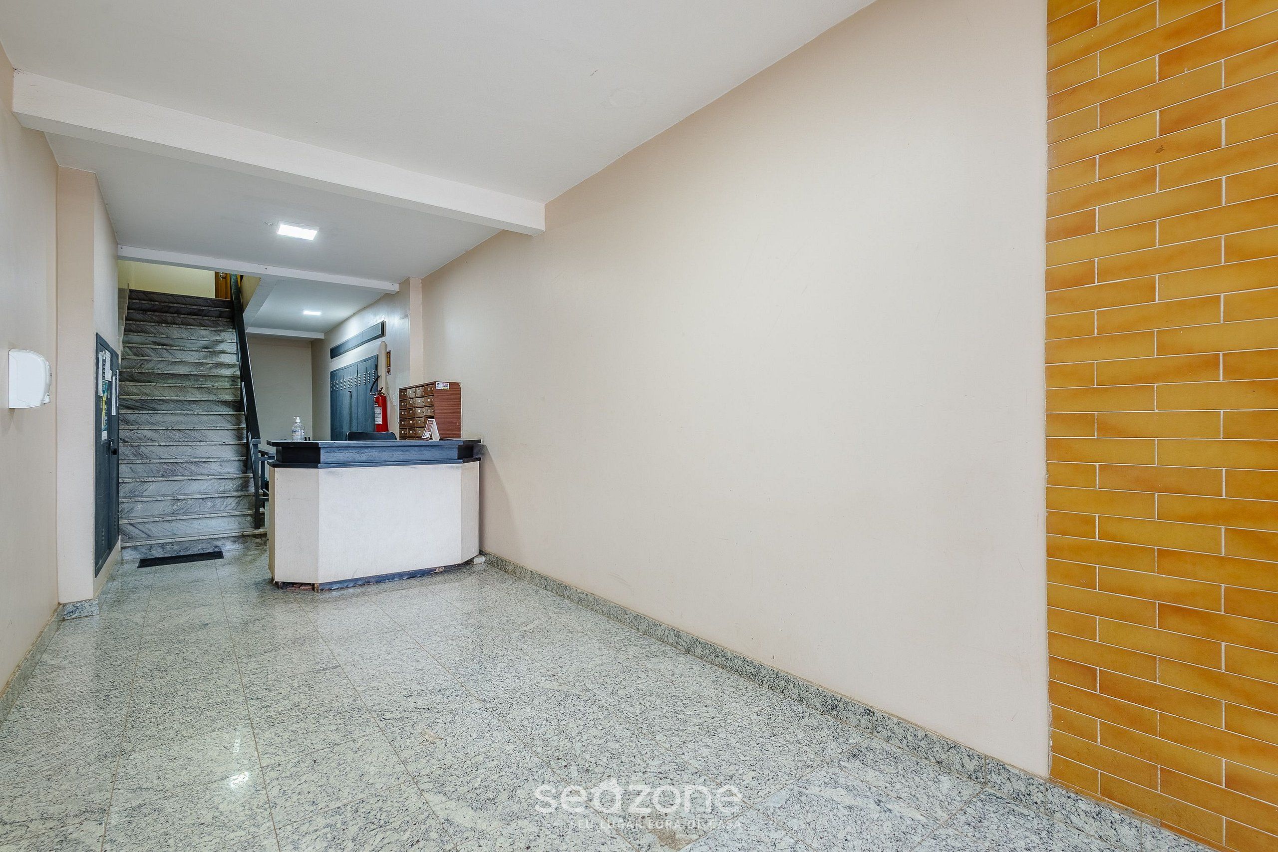 Un pasillo con una recepción, una escalera y una pared de ladrillo.