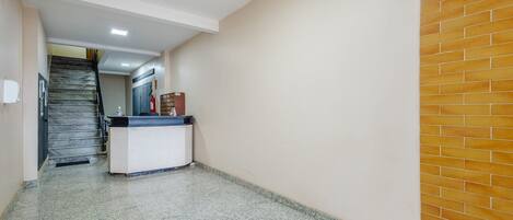 A hallway with a reception desk, a staircase, and a brick wall.