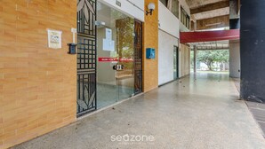 A corridor with a brick wall, a glass door with a metal gate, and a red awning. - Condominium With Excellent Location in Asa Norte - Amzs (Brasília)