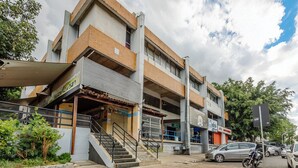 A multi-story building with a staircase leading to the entrance, a parked motorcycle, and a car on the street. - Condominium With Excellent Location in Asa Norte - Amzs (Brasília)