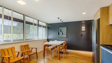 Una cocina moderna con armarios de madera, un refrigerador empotrado y un comedor con sillas y mesa de madera.