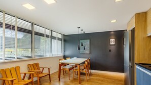 A modern kitchen with wooden cabinets, a built-in refrigerator, and a dining area with wooden chairs and a table. - Condominium With Excellent Location in Asa Norte - Amzs (Brasília)