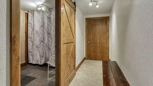 Un pasillo con una puerta de madera, una lámpara en el techo y una cortina estampada.