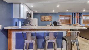 Una cocina moderna con encimera de granito, electrodomésticos de acero inoxidable y taburetes de bar.