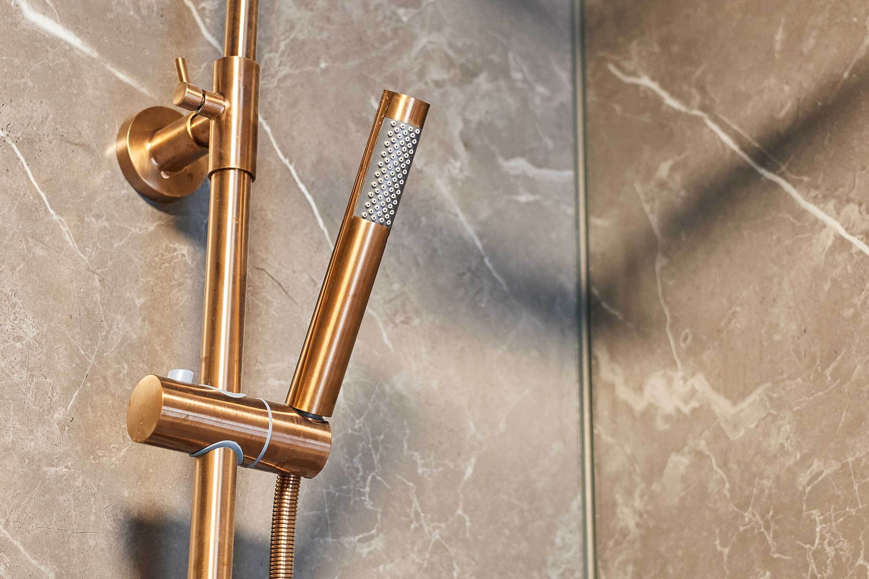 Une douche équipée d’un pommeau de douche à main et d’un robinet de contrôle fixé au mur.
