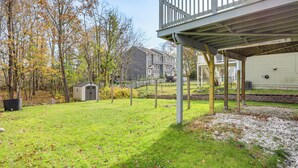 A backyard with a wooden deck, a small shed, and a grassy area with trees.