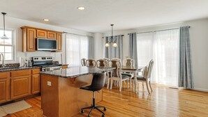 A modern kitchen with wooden cabinets, a large island, and a dining area with a table and chairs.