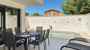 A patio with a table and chairs, a pool, and a building in the background. - Awesome home in Vodnjan (Vodnjan)
