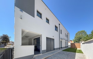 Un bâtiment moderne à deux étages, doté d’un toit plat, de grandes fenêtres et d’une allée pavée.
