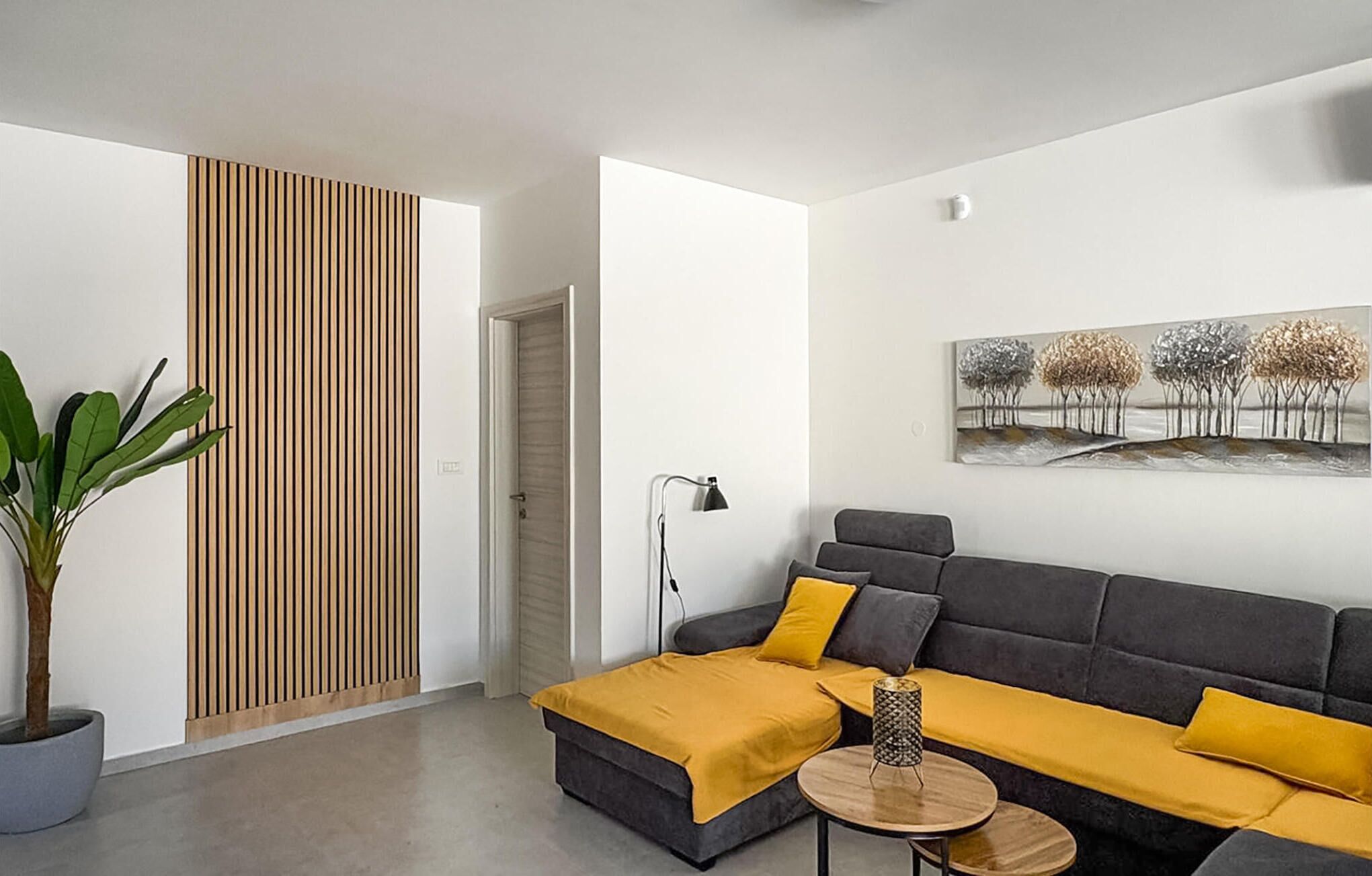 Una sala moderna con un sofá, una mesa de centro, una lámpara y un cuadro en la pared.
