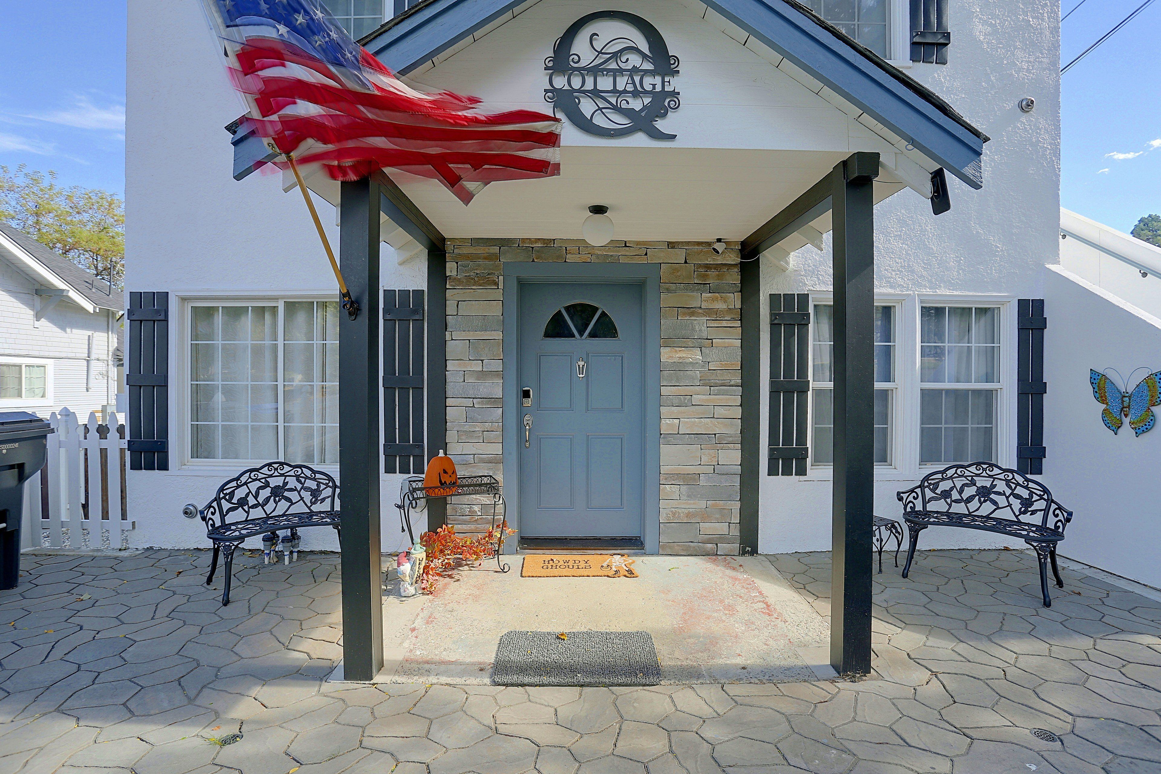 A cottage with a stone facade, a blue door, and a sign above the entrance.