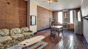 A spacious living area with a brick wall, a ceiling fan, and a dining area with a table and chairs. - Convenient Couple's Retreat in Dtwn Marshall! (Marshall)