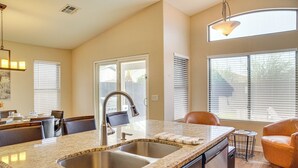 A kitchen with a granite countertop, double sink, and a dining area with a chair and table. - 2 Mi to Surprise Stadium! Snowbird Haven w/ Pool (Surprise)