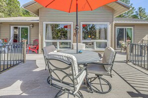 Eine Terrasse mit Tisch, Stühlen und Sonnenschirm, mit Blick auf das Haus.