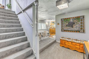 Eine Treppe führt zu einem Schlafzimmer mit einem Bett, einem Schminktisch und einem Bild an der Wand.