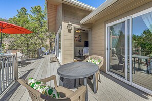 Eine überdachte Terrasse mit Tisch und Stühlen, einem roten Sonnenschirm und einer Glasschiebetür, die auf eine Terrasse führt.