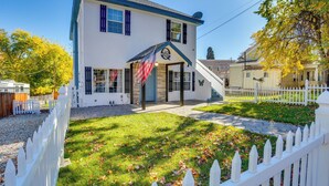 A two-story building with a white facade and blue trim, featuring a front entrance with a small porch and an American flag. - Pet-Friendly Susanville Home w/ Pickleball Court (Susanville)