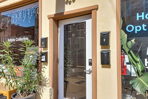 Un escaparate con puerta de vidrio, plantas en macetas y un cartel que dice "Artists Collective".