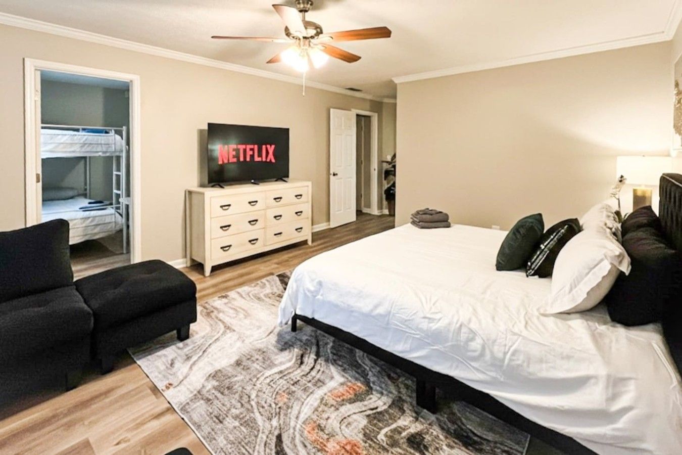 Ein Schlafzimmer mit Bett, Fernseher, Kleiderschrank und Deckenventilator.