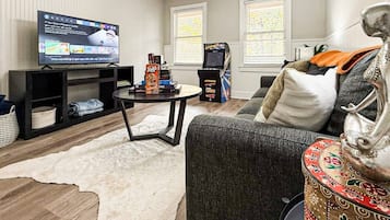 A living room with a television, gaming console, sofa, and decorative items.