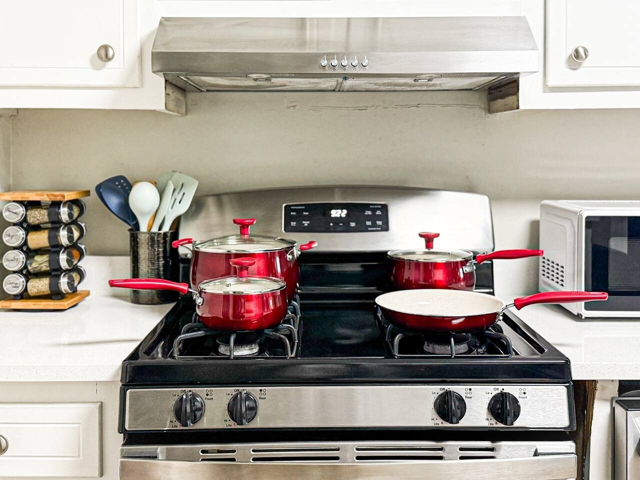 A kitchen with a stove, pots, a microwave, and a spice rack.