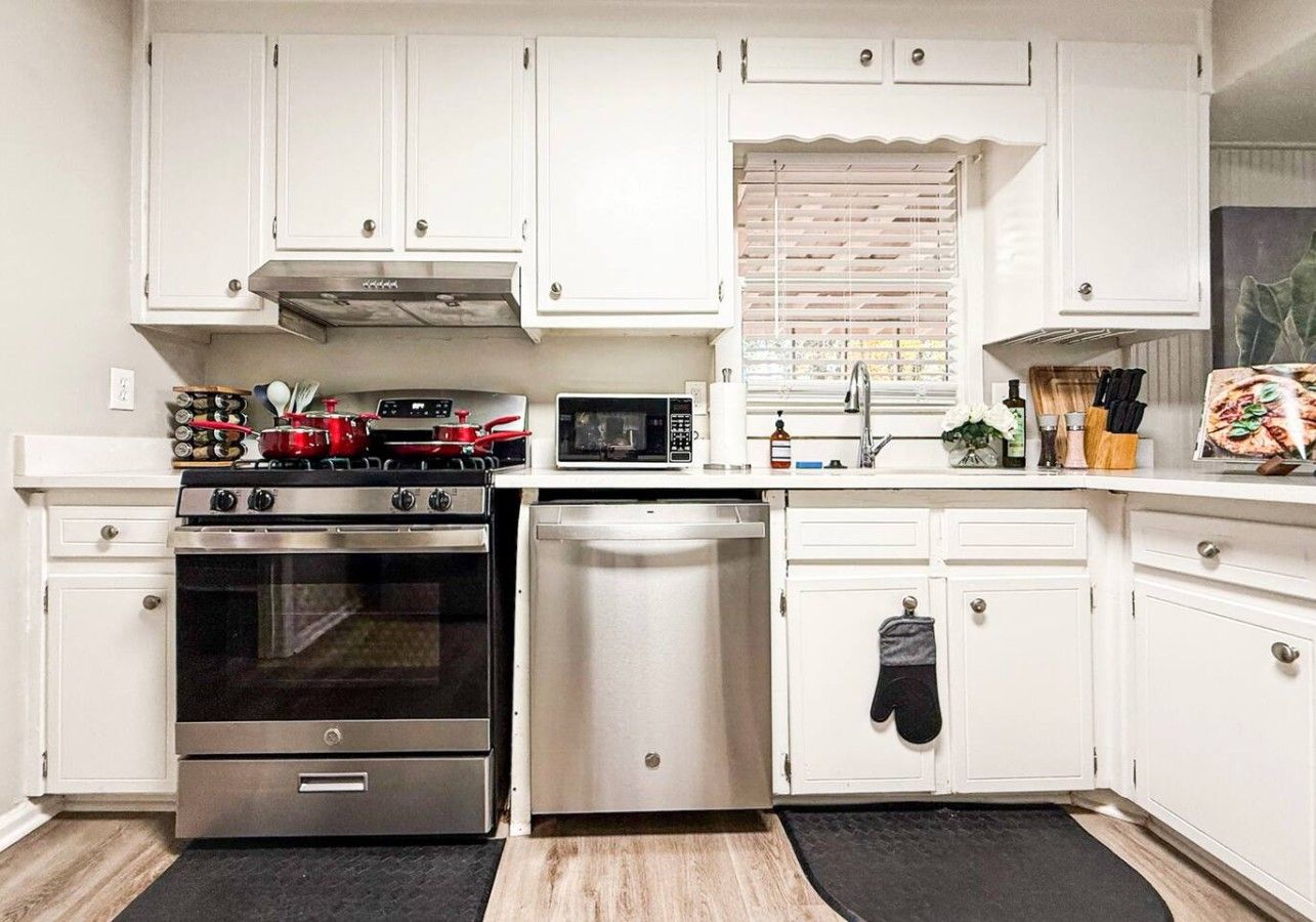 A kitchen with white cabinets, a stainless steel stove, a microwave, and a dishwasher.