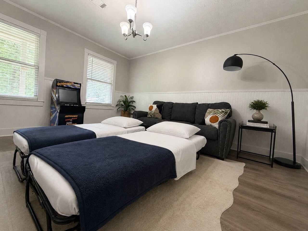 A hotel room with two beds, a desk, a chair, a lamp, and a television.