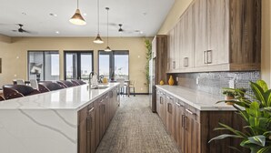A modern kitchen with a large island, wooden cabinets, and pendant lighting. - Trendy 1BR w/ 10ft Ceilings+FREE Parking+ Pets OK (Dallas)