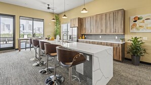A modern kitchen with a marble island, bar stools, wooden cabinets, and pendant lighting. - Trendy 1BR w/ 10ft Ceilings+FREE Parking+ Pets OK (Dallas)