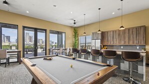 A pool table with a city view, a bar area with stools, and a seating area with chairs. - Trendy 1BR w/ 10ft Ceilings+FREE Parking+ Pets OK (Dallas)