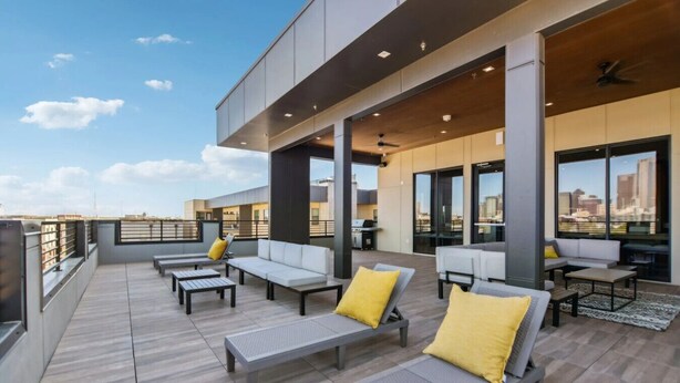 A rooftop terrace with outdoor seating, a city view, and a modern architectural design. - Trendy 1BR w/ 10ft Ceilings+FREE Parking+ Pets OK (Dallas)