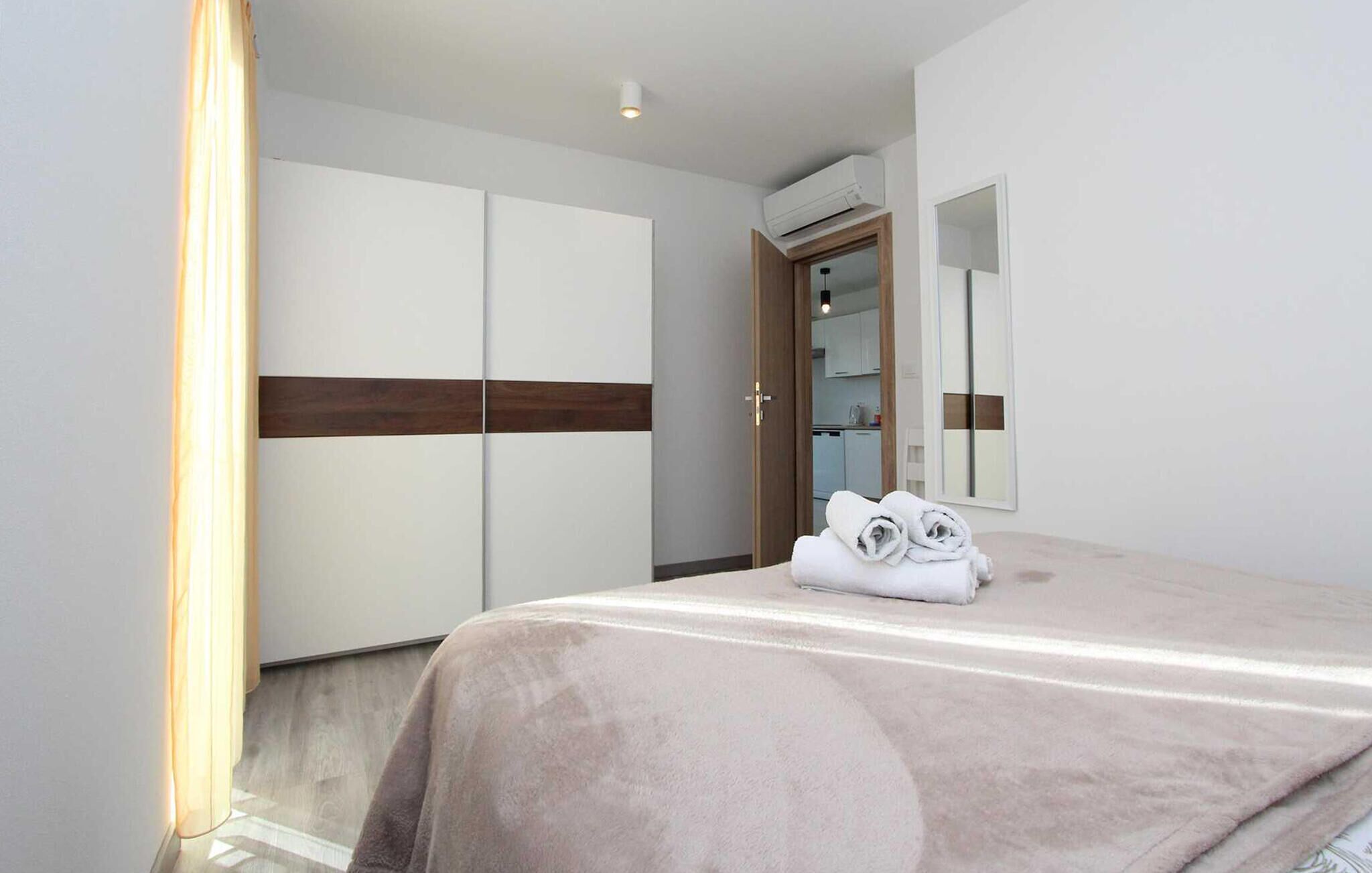 Ein Hotelzimmer mit Bett, Kleiderschrank, Spiegel und Klimaanlage.