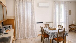 A dining area with a table set for four, chairs, a buffet table, and a kitchen area with a microwave. - La Corte Guesthouse – Independent stay with private garden near Milan (Cornate d'Adda)