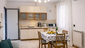 A compact living space with a kitchenette, dining area, and a sofa. - La Corte Guesthouse – Independent stay with private garden near Milan (Cornate d'Adda)