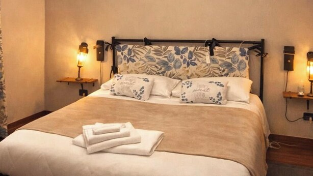 A neatly made bed with a floral headboard, two bedside lamps, and a pair of folded towels. - La Corte Guesthouse – Independent stay with private garden near Milan (Cornate d'Adda)