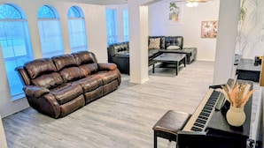 Un salon avec un canapé en cuir marron, un piano noir et une table basse.