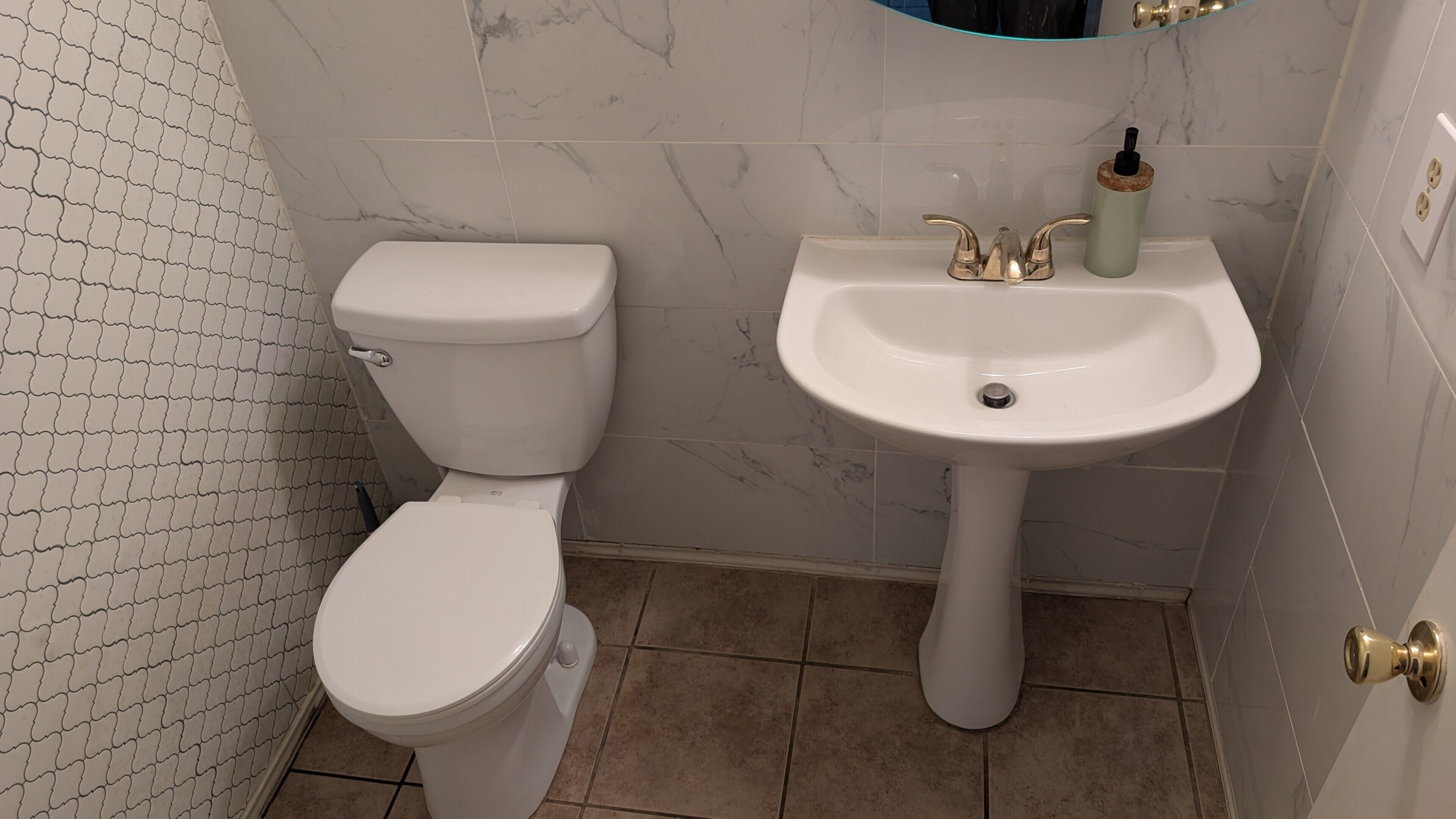 A bathroom with a toilet, sink, and marble tiles.