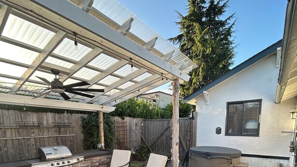 Un patio à l’arrière de la maison, équipé d’un barbecue, de meubles d’extérieur et d’un espace abrité.