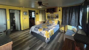 Une chambre à coucher avec un lit, un ventilateur de plafond, un bureau et une chaise.