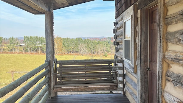A wooden cabin with a porch, a wooden bench, and a view of a green field and trees. - Come stay on the farm, pet friendly! music city, galax va. Blue ridge mountains. (Galax)