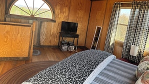 Una camera accogliente con un letto, una televisione e una finestra con tende a quadri.