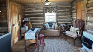 A rustic cabin interior with a wooden dining table, a sofa, a chair, a fireplace, and a window with a view. - Come stay on the farm, pet friendly! music city, galax va. Blue ridge mountains. (Galax)
