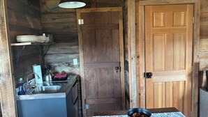 A rustic kitchen with wooden walls, a sink, and a table with a bowl. - Come stay on the farm, pet friendly! music city, galax va. Blue ridge mountains. (Galax)