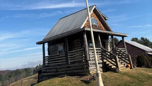 A rustic log cabin with a metal roof, a wooden staircase, and a flagpole with a red flag. - Come stay on the farm, pet friendly! music city, galax va. Blue ridge mountains. (Galax)