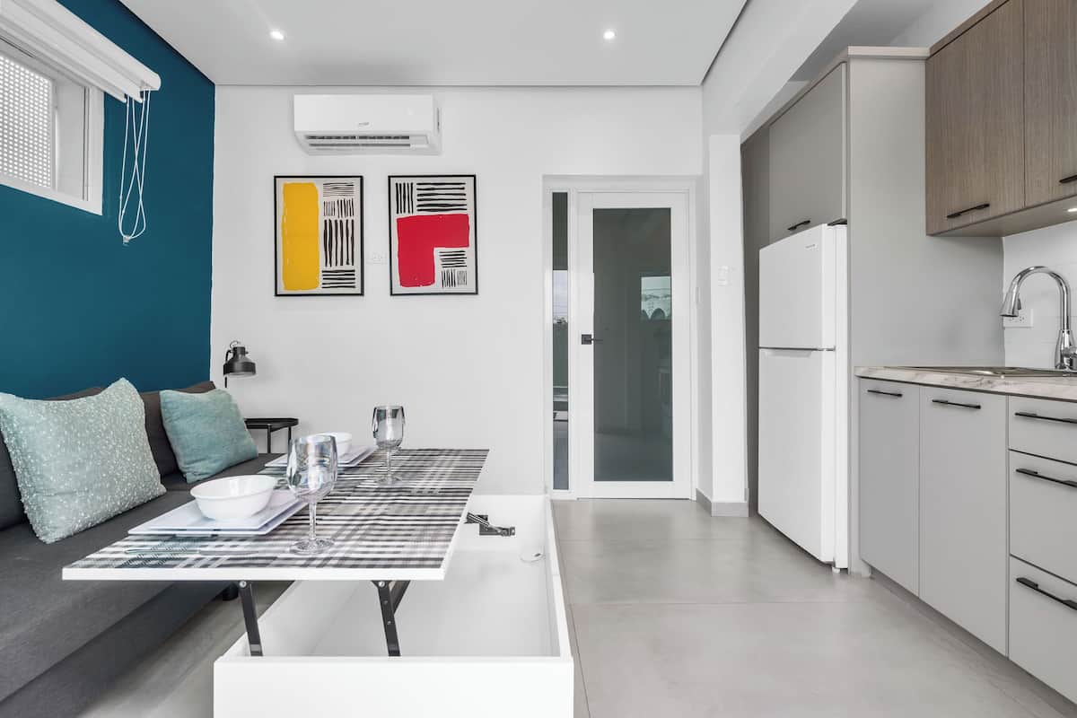 Una cucina moderna con mobili bianchi, un frigorifero bianco e un'area pranzo con tavolo e sedie.