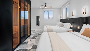 A modern hotel room with two beds, a ceiling fan, a large window, and a view of the cityscape. - Casa Placita Hotel (San Juan)