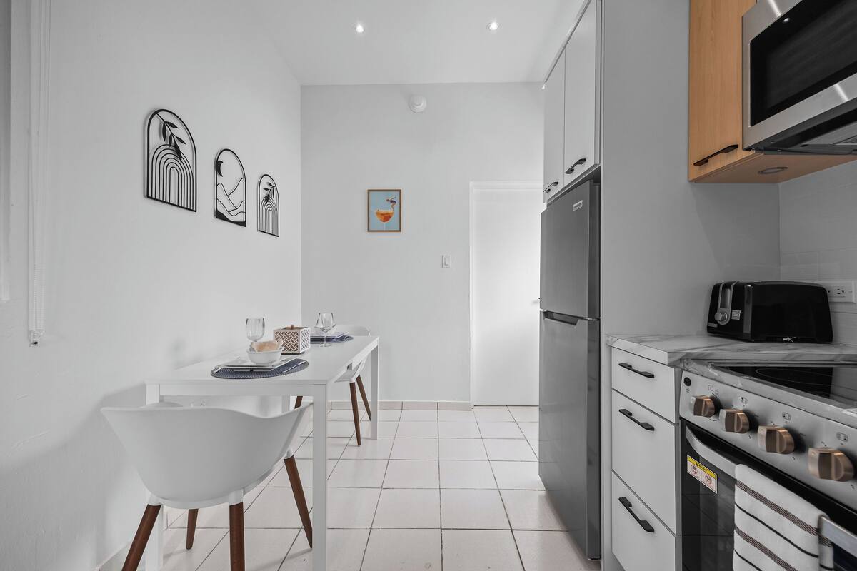 Una cucina moderna con mobili bianchi, forno integrato e microonde.