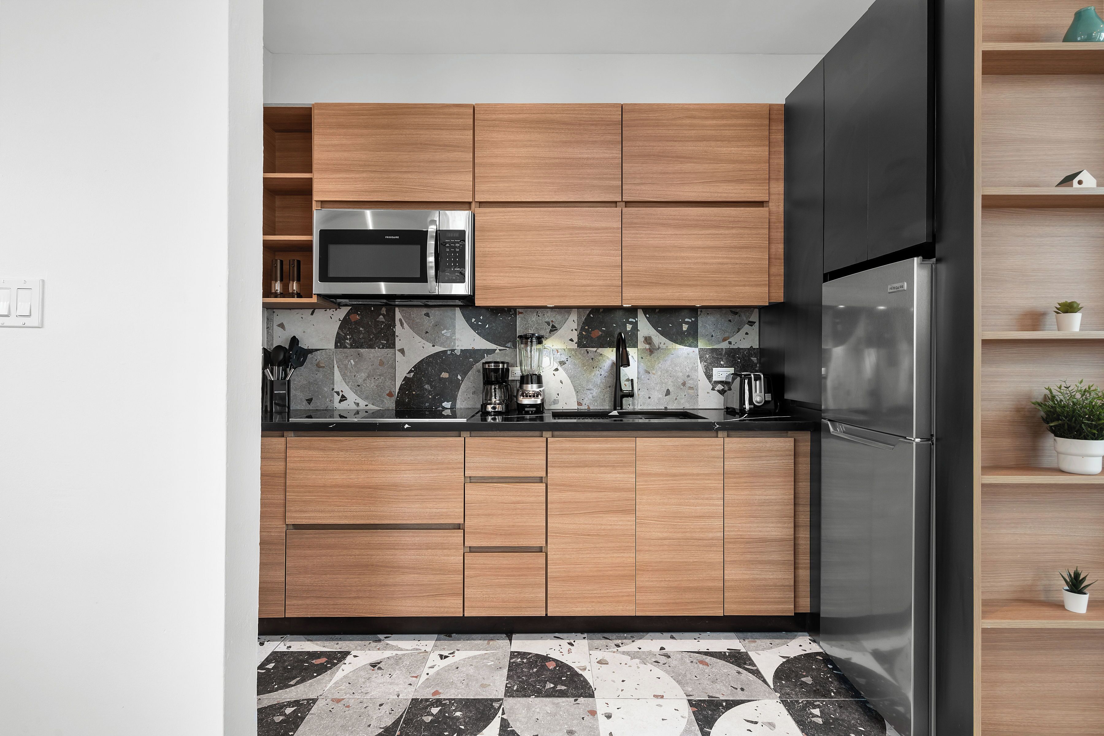 Una cocina moderna con armarios de madera, un refrigerador de acero inoxidable y un microondas.