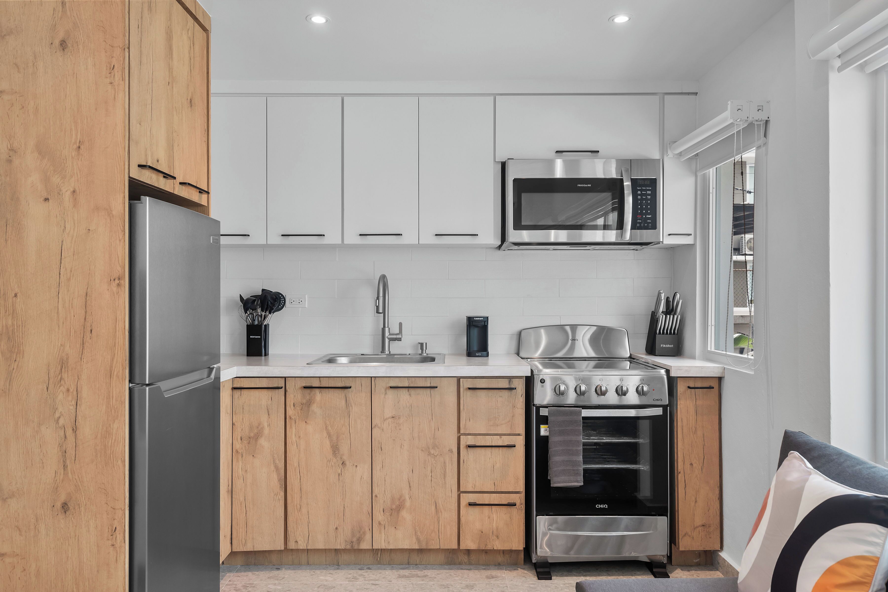 A modern kitchen with wooden cabinets, stainless steel appliances, a microwave, and a built-in oven.
