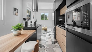 A modern kitchen with a large stainless steel refrigerator, a wooden countertop, and a potted plant. - Casa Placita Hotel (San Juan)